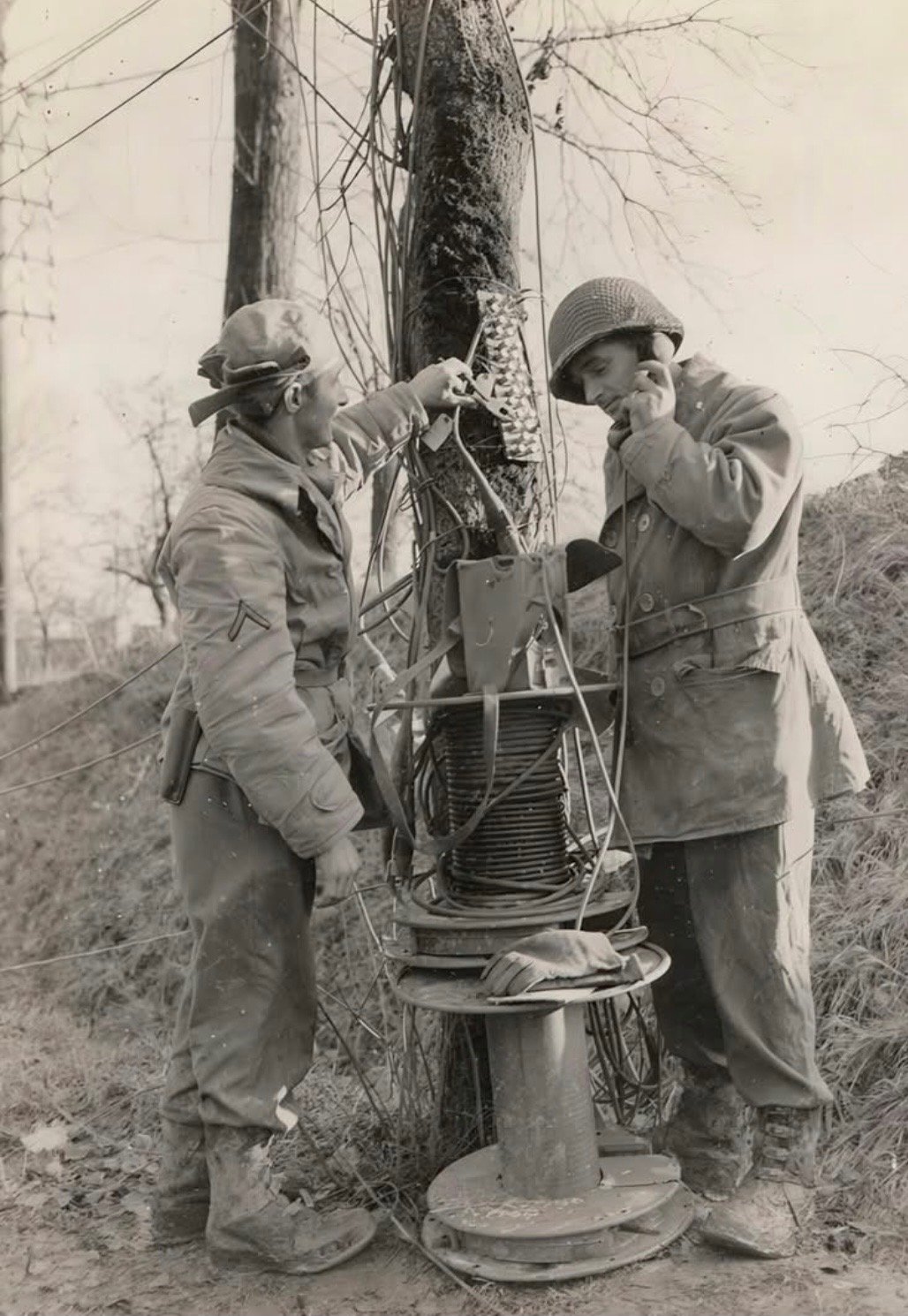 Two U.S. Army Signal Corps soldiers laying field telephone wire in Europe during World War II